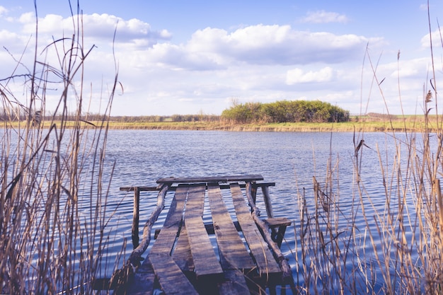 Vieux pont en bois près de la rivière sur le fond d'un beau ciel