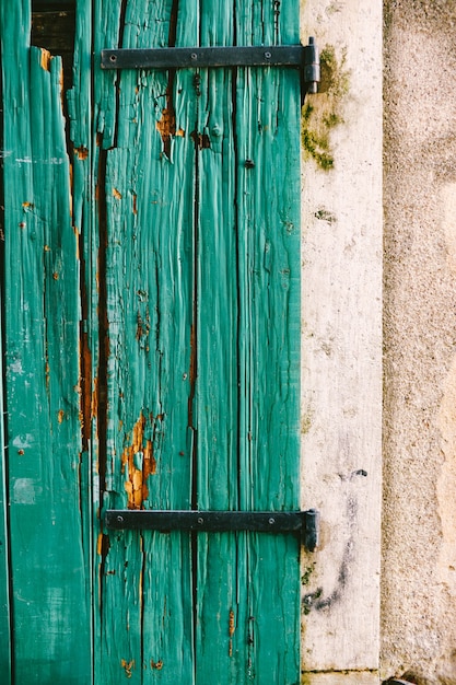 Un vieux portillon vert fissuré fixé à un mur blanc