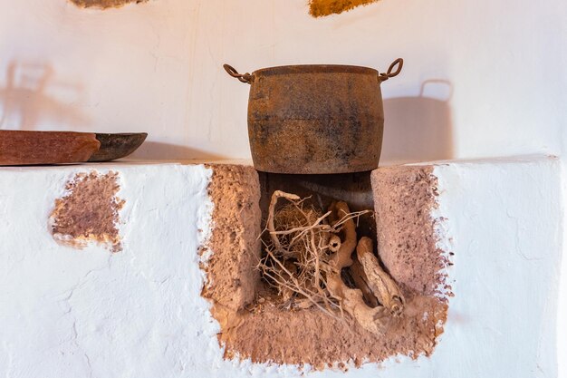 Vieux pot en argile avec de l'eau et des racines sur un fond de mur blanc.