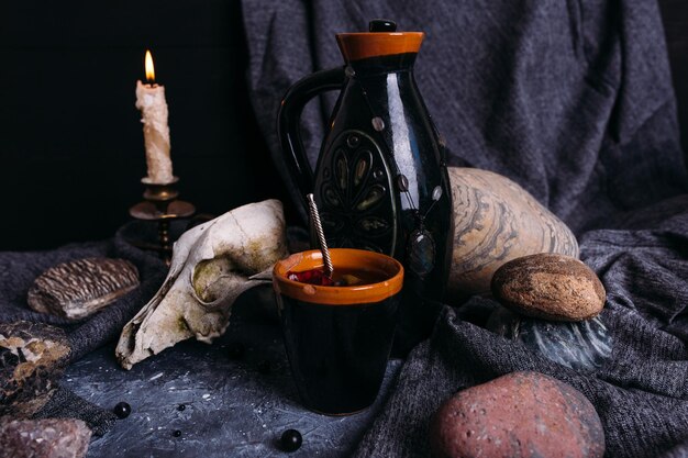 Photo vieux pot de crâne de chien et pierres sur la table de la sorcière boisson enchantée avec des pétales de fleurs