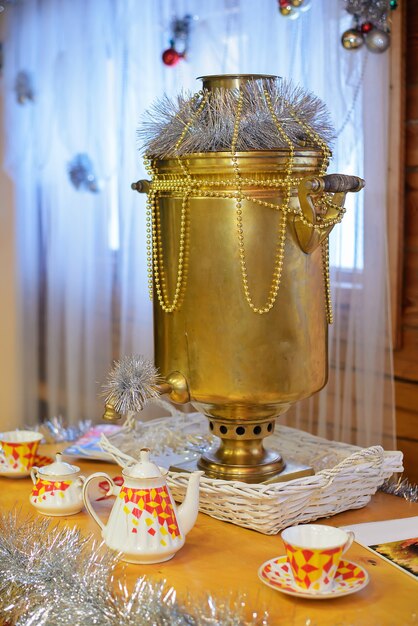 Photo le vieux samovar jaune, décoré pour le nouvel an est sur la table avec des ustensiles pour le thé