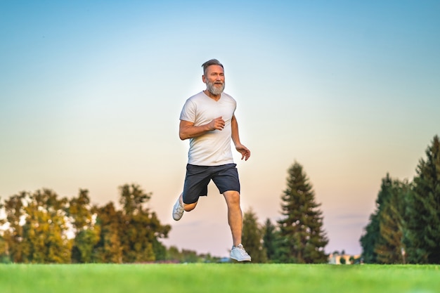 Le vieux sportif courant sur l'herbe