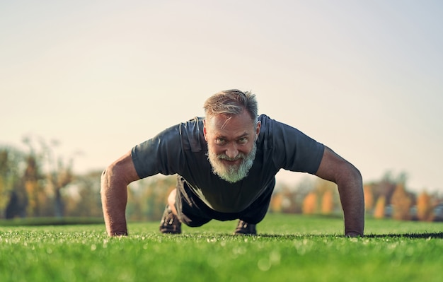 Le vieux sportif poussant sur l'herbe