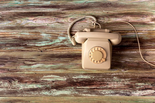 Vieux téléphone gris avec numéroteur de disque sur un gros plan de table en bois