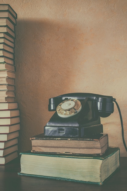 Vieux téléphone noir et une pile de livres