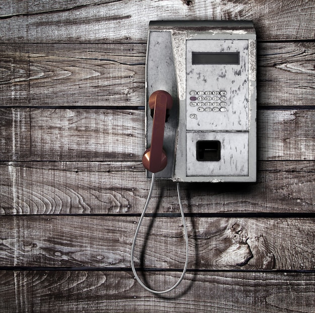 Vieux téléphone public sur fond de bois