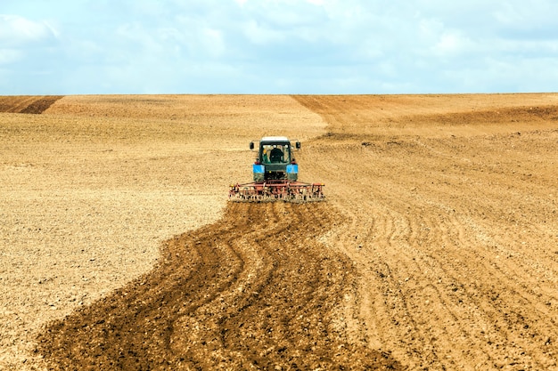 Photo un vieux tracteur laboure le sol dans un champ tout en préparant le champ pour l'ensemencement