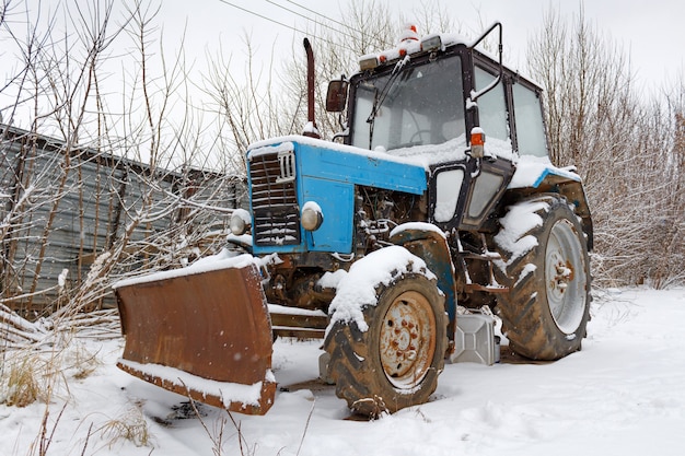 Vieux tracteur rouillé sur sol enneigé