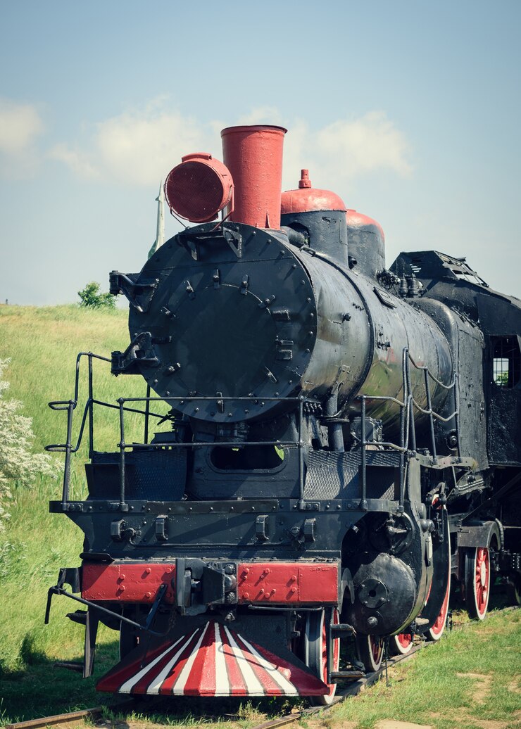 Photo vieux train classique au tube rouge sur un fond d'herbe verte.