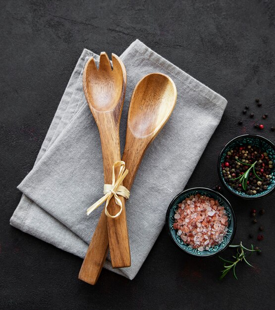 Vieux ustensiles de cuisine vintage. Cuillères en bois, serviette et épices sur fond noir. Vue de dessus