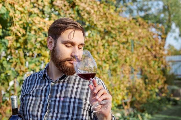 Vigneron du Caucase, boire du vin rouge en verre, le déguster en vérifiant la qualité debout dans les vignes