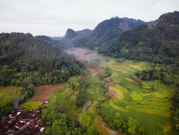 Photo un village dans les montagnes avec un champ vert et un village en arrière-plan