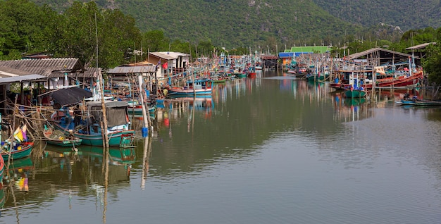 Village de pêcheurs en ThaïlandeLes bateaux de pêche flottent dans l'eau au port du village de pêcheurs