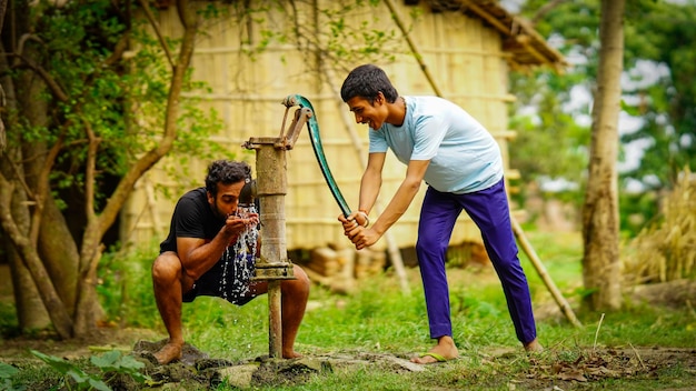 Village et sauvez le concept de l'eau garçon buvant de l'eau à l'aide d'une pompe à main dans le village