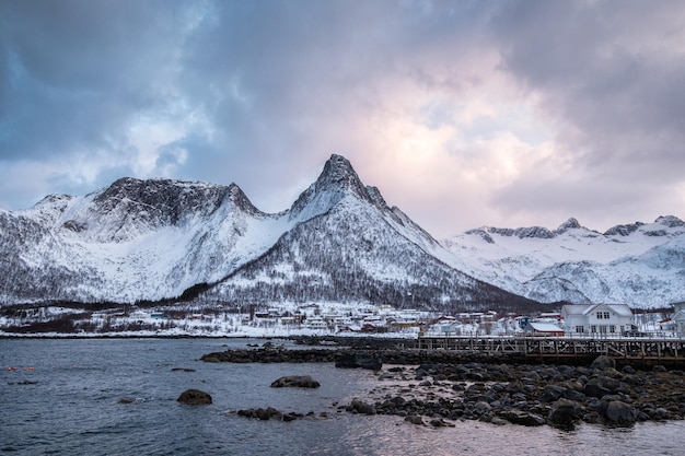 Photo village scandinave sur le littoral avec montagne enneigée en arrière-plan à l'île de mefjord brygge senja norvège