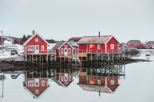 Photo village scandinave avec reflet de la maison rouge sur l'océan arctique