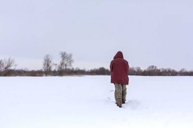 Un villageois marche en hiver dans le champ