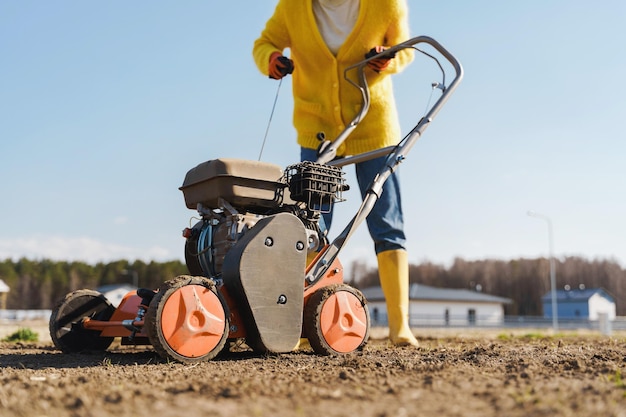 Une villageoise utilise un aérateur pour la scarification et l'aération de la pelouse ou du pré