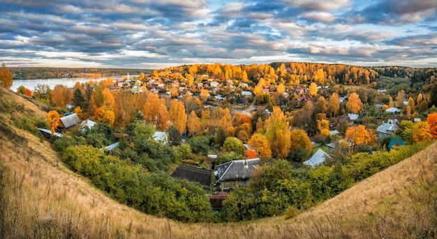 Ville d'automne de Plyos depuis la hauteur de la cathédrale Maisons de montagne et arbres jaunes et Volga