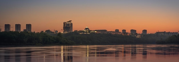 Photo ville du soir au bord de la rivière panorama orange lever ou coucher de soleil sur la ville