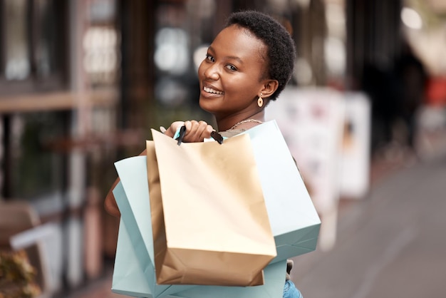 La ville du sourire et le portrait d'une femme noire avec un sac d'achat pour le commerce de boutique et le giveaway Une personne heureuse et un client avec des vêtements de créateurs pour la vente au détail et la vente à prix réduit de luxe au Nigeria