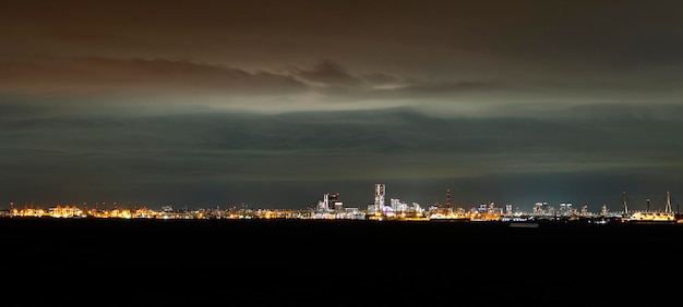 Ville éclairée par la mer contre un ciel nuageux la nuit
