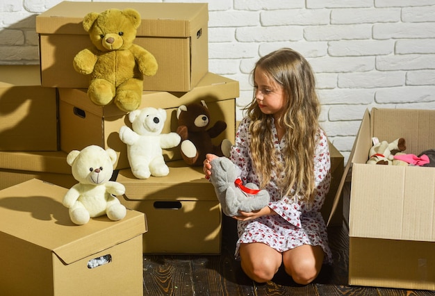 Photo où la ville est votre arrière-cour petite fille heureuse avec jouet achat d'une nouvelle habitation boîtes en carton déménageant dans une nouvelle maison enfant heureux boîte en carton jouant dans une nouvelle maison nouvel appartement