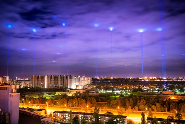 Ville illuminée de nuit avec des lumières bleues dans les nuages et le ciel