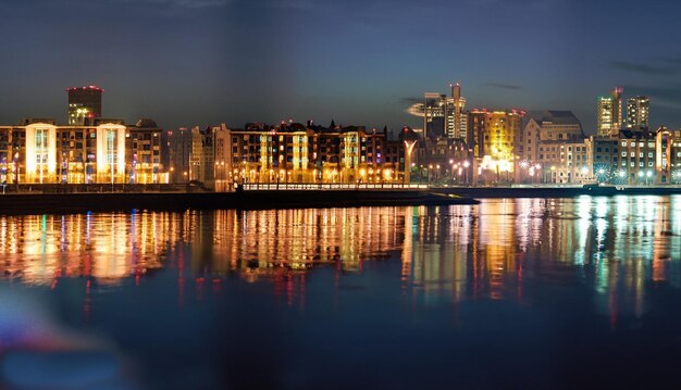 La ville de nuit se dresse sur la rivière et les lumières des fenêtres peuvent être vues dans le reflecti