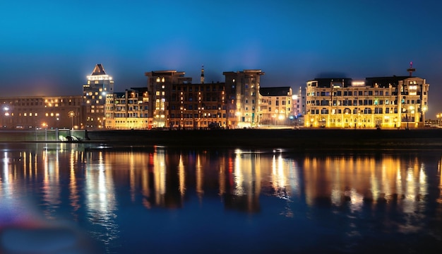 La ville de nuit se dresse sur la rivière et les lumières des fenêtres peuvent être vues dans le reflecti