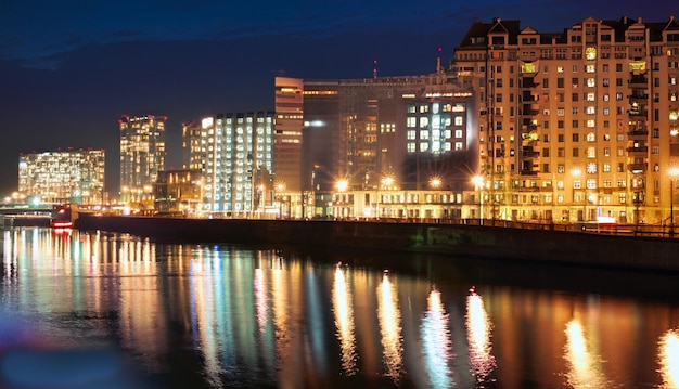 La ville de nuit se dresse sur la rivière et les lumières des fenêtres peuvent être vues dans le reflecti