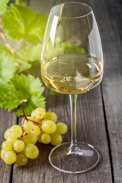 Vin blanc dans un verre et une grappe de raisin