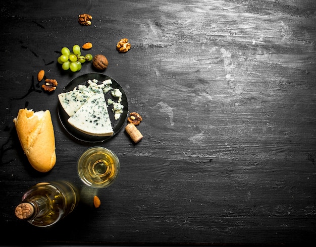 Vin blanc avec fromage bleu français et noix. Sur planche de bois noire