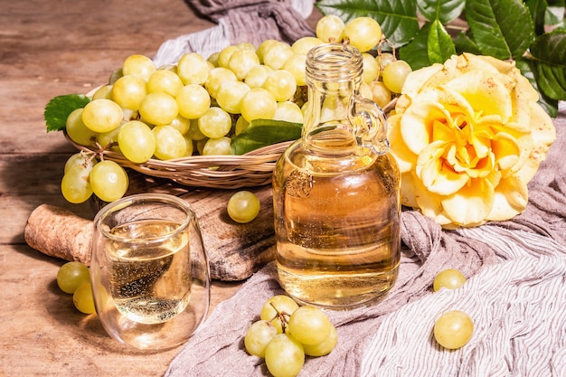 Vin blanc et raisin dans un panier en osier. Fruits frais, verre et bouteille. Lumière dure moderne, ombre sombre. Vieux fond de planches de bois, espace de copie