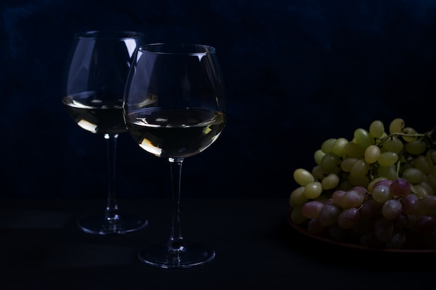 Vin blanc et raisins sur une surface sombre