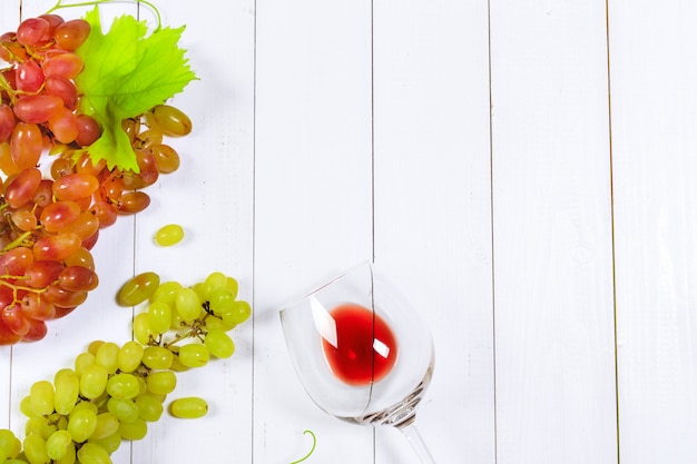 Photo vin avec des branches de raisins blancs. sur une table en bois