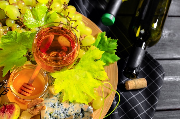 Vin avec des branches de raisins blancs. Sur une table en bois