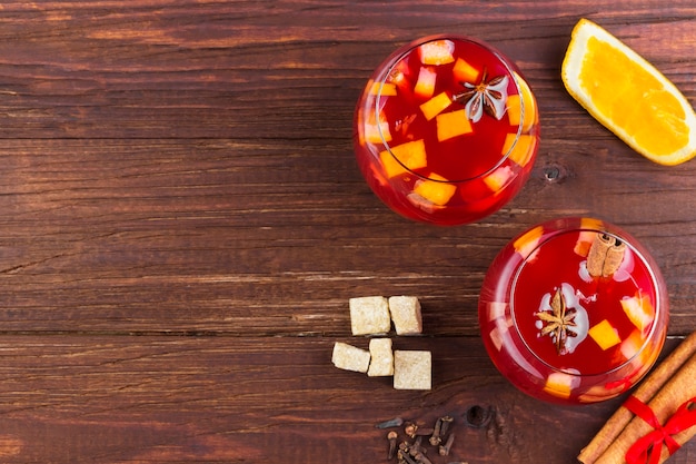 Vin chaud aux agrumes dans un verre sur du bois foncé, vue de dessus, espace de copie