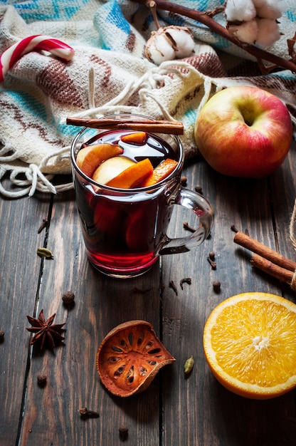 Vin chaud aux épices, pomme et orange sur fond de bois