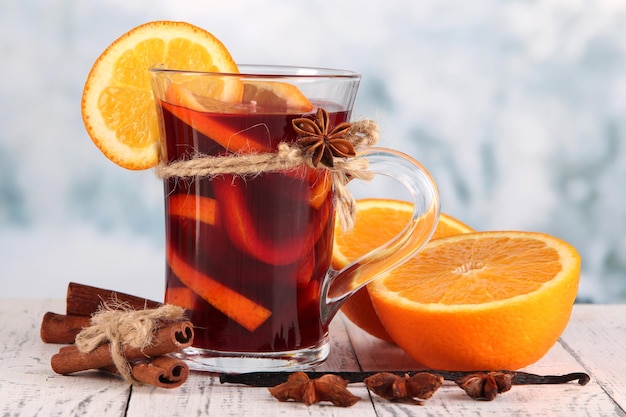 Vin chaud aux oranges et épices sur table sur fond clair