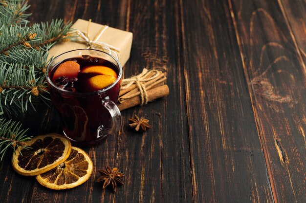 Vin chaud, cadeau et épices sur la table à côté de l'arbre