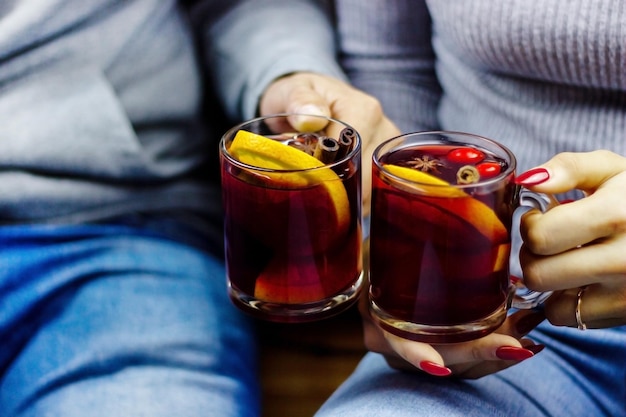 Vin chaud chaud dans les mains des hommes et des femmes, épices.