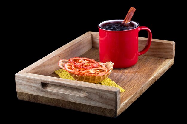 Vin chaud avec chips de tomates sur une planche de bois sur fond noir