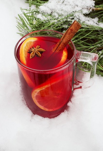 Vin chaud dans la rue dans la neige avec une branche de pin