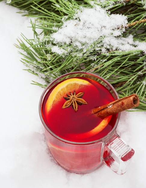 Vin chaud dans la rue dans la neige avec une branche de pin