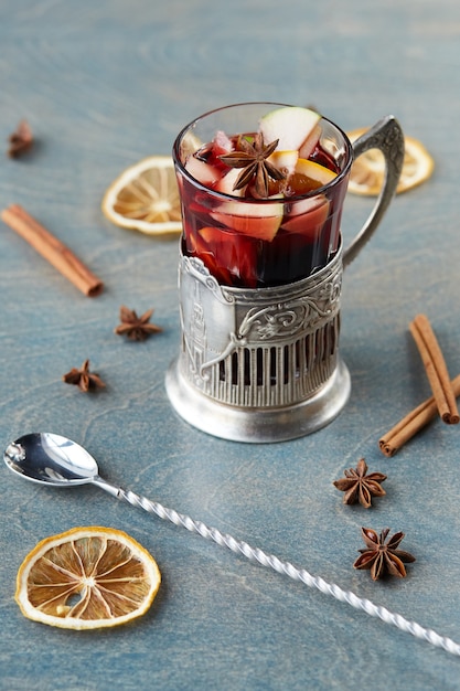 Vin chaud dans un verre sur une table en bois. Décoré avec du noir, de la cannelle et du citron