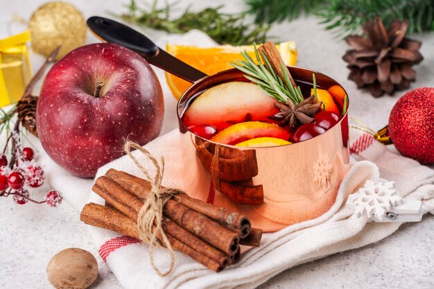 Vin chaud avec des fruits et des épices dans un pot en cuivre