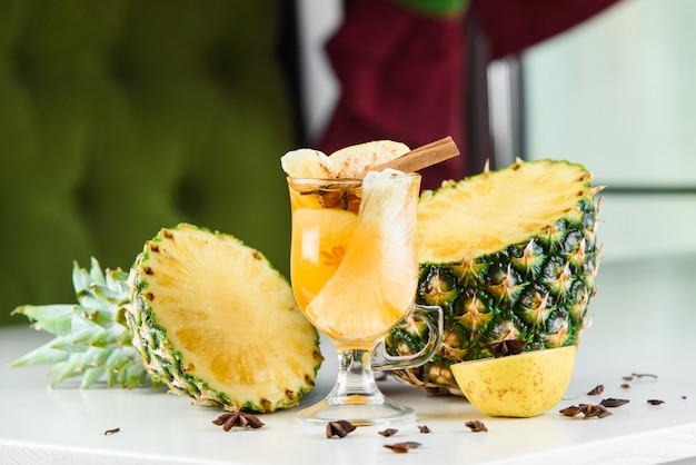 Vin chaud, grog et punch boissons alcoolisées chaudes sur la table avec décoration de saison: ananas, cannelle, pomme, orange, anis étoilé. Boisson épicée de saison.