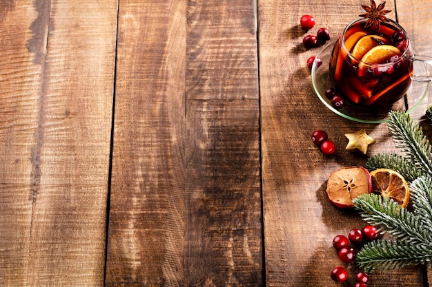 Photo vin chaud de noël aux épices sur une table rustique en bois.