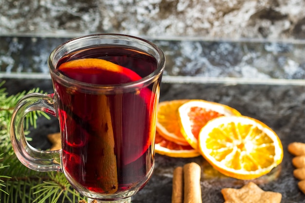 Vin chaud de Noël avec des biscuits au gingembre orange cannelle clou de girofle anis et sapin sur le tableau noir foncé